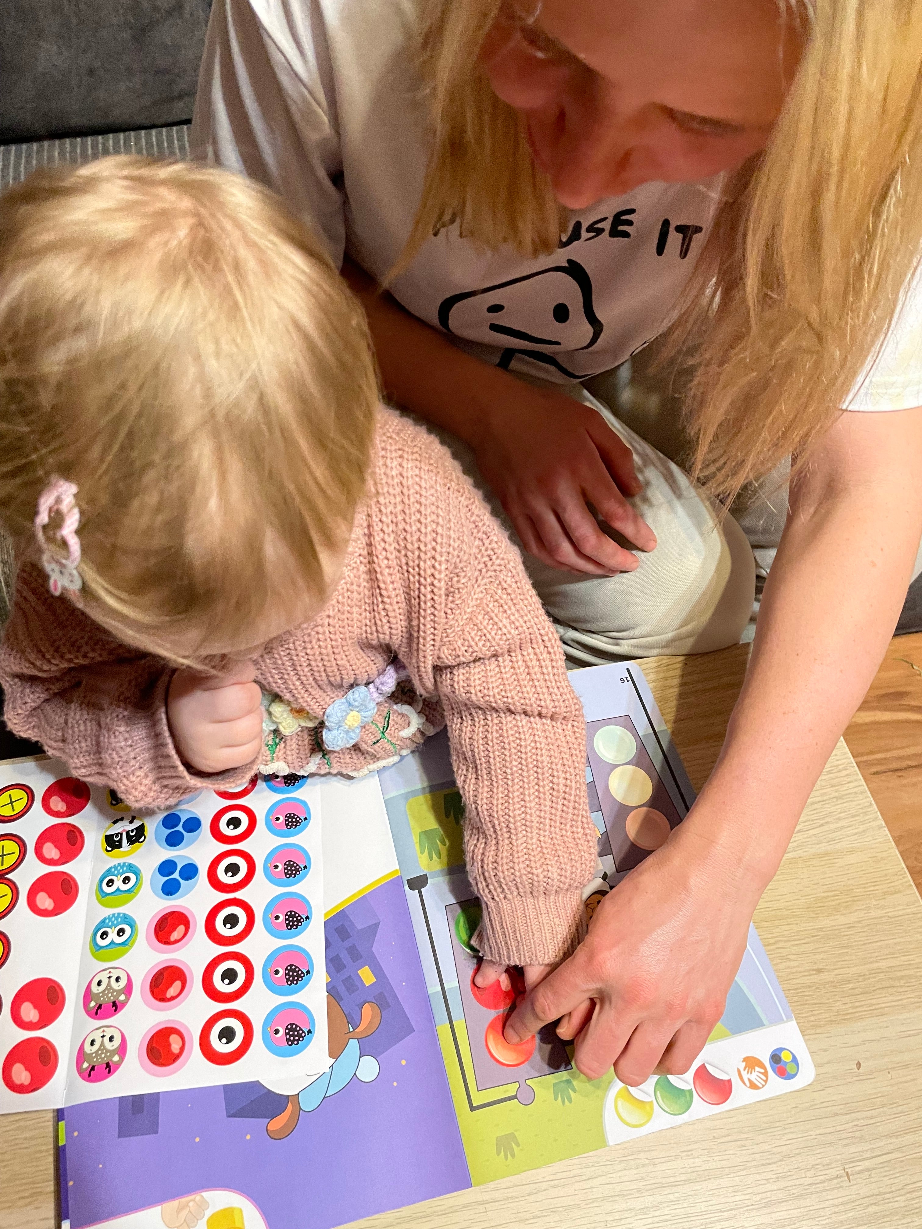 Jauns zēns ar brillēm spēlējas un rāda īkšķus uz augšu, krāsojot multfilmas dzīvnieku aktivitāšu lapu telpās.