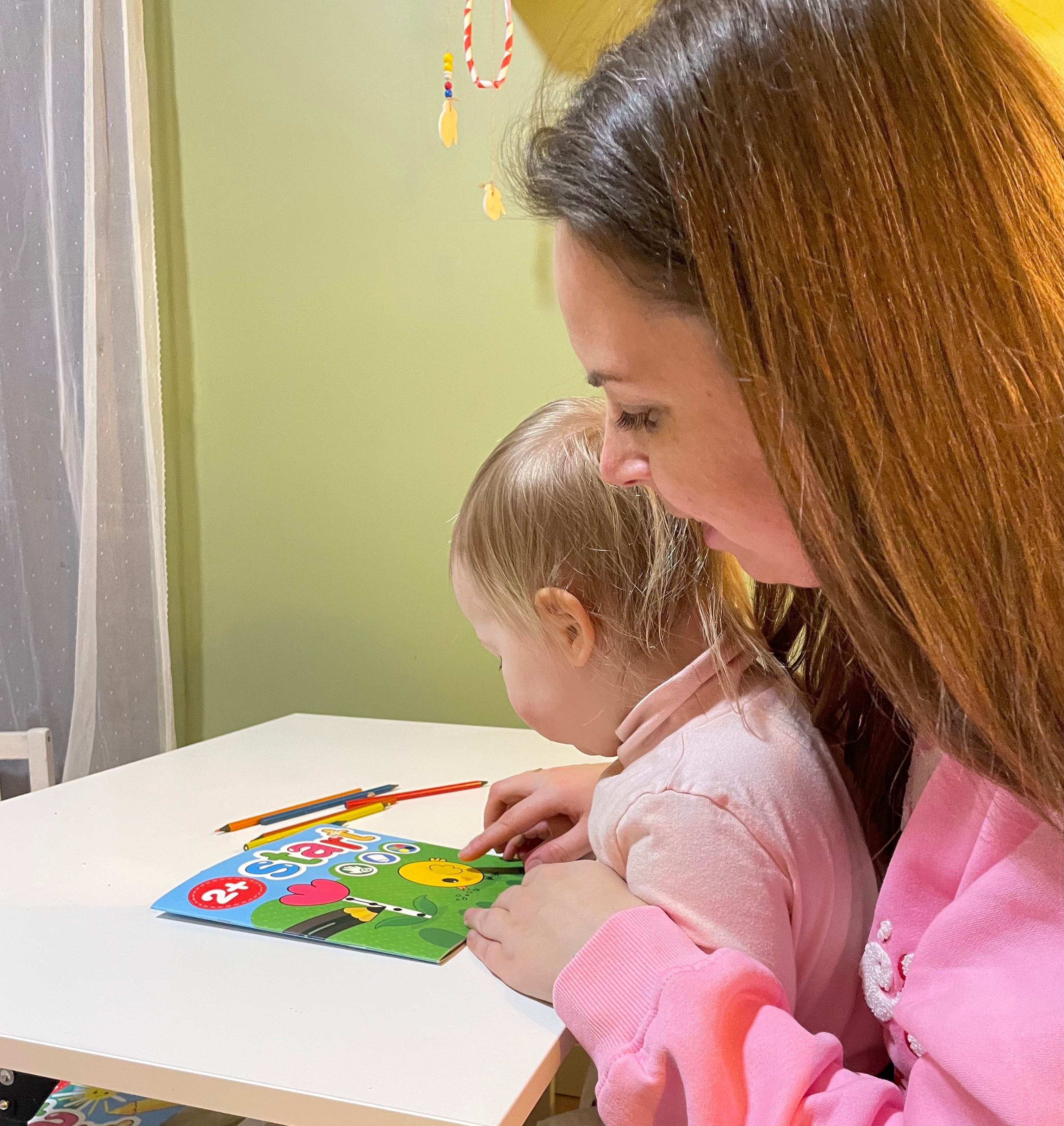 Jauns zēns ar brillēm spēlējas un rāda īkšķus uz augšu, krāsojot multfilmas dzīvnieku aktivitāšu lapu telpās.